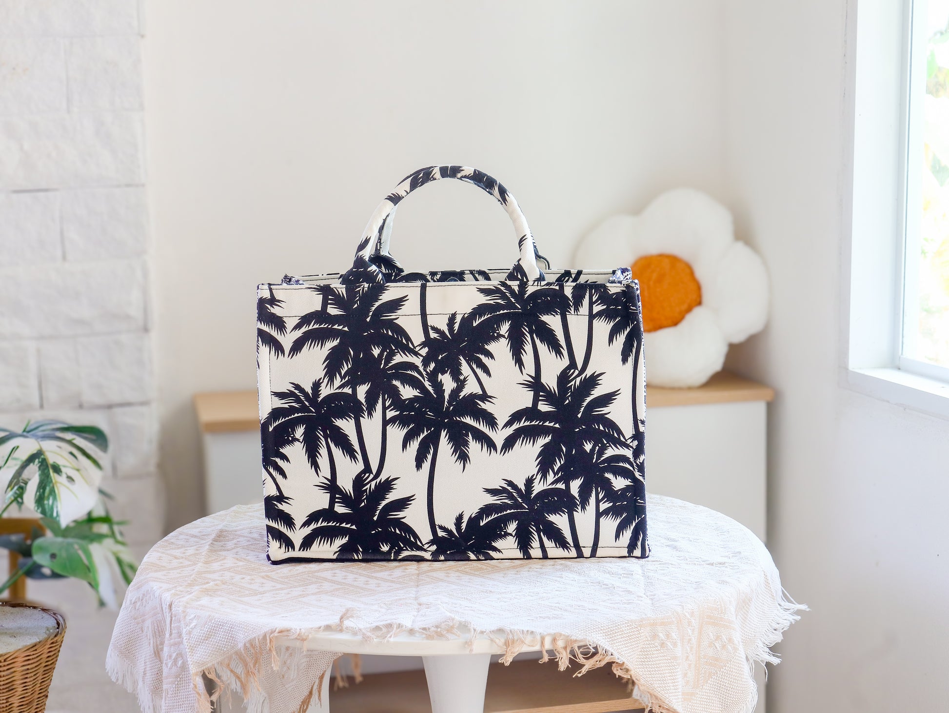 Tote bag with palm tree pattern on a white stool in a bright room