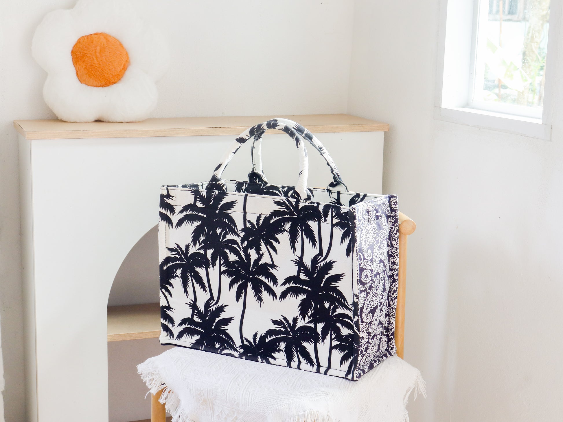 Tote bag with palm tree pattern on a chair in a bright room