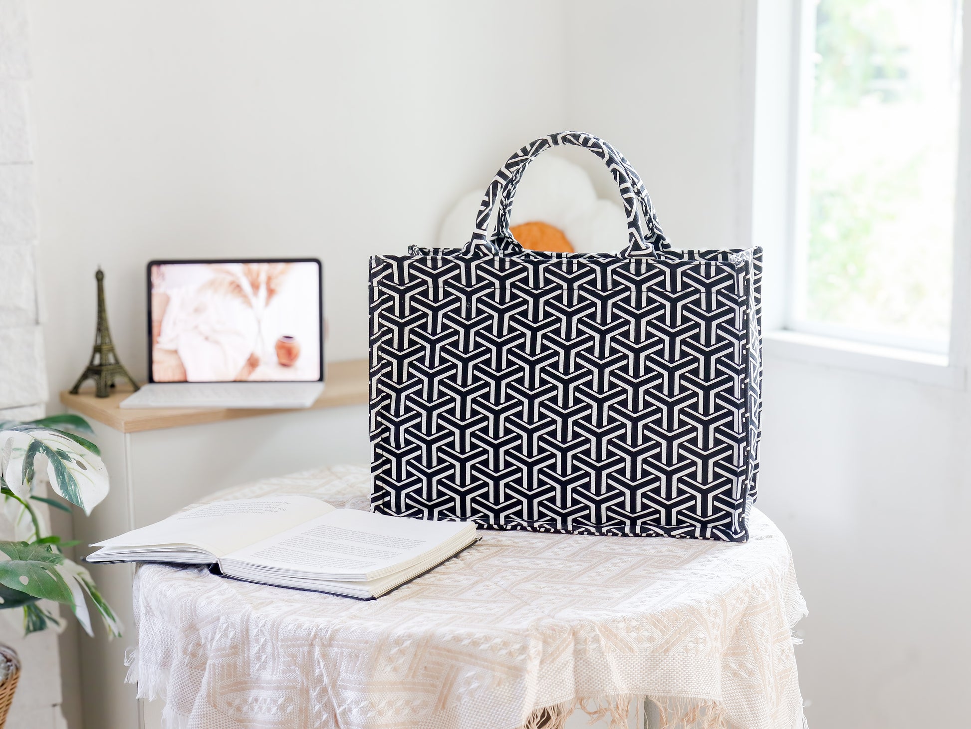 Black and white patterned bag on a table with a computer monitor in the background