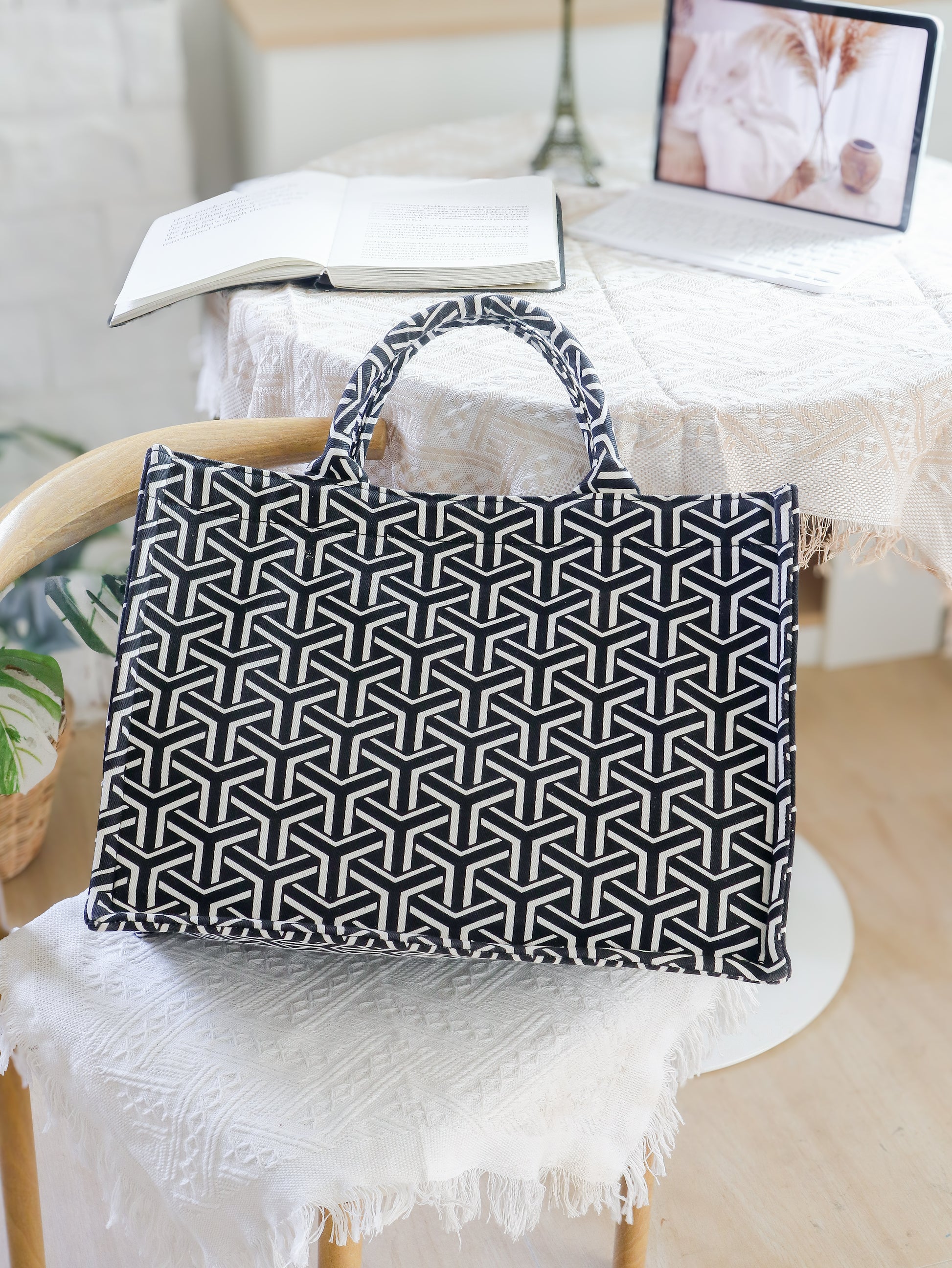 Black and white geometric patterned bag on a chair with a blurred background