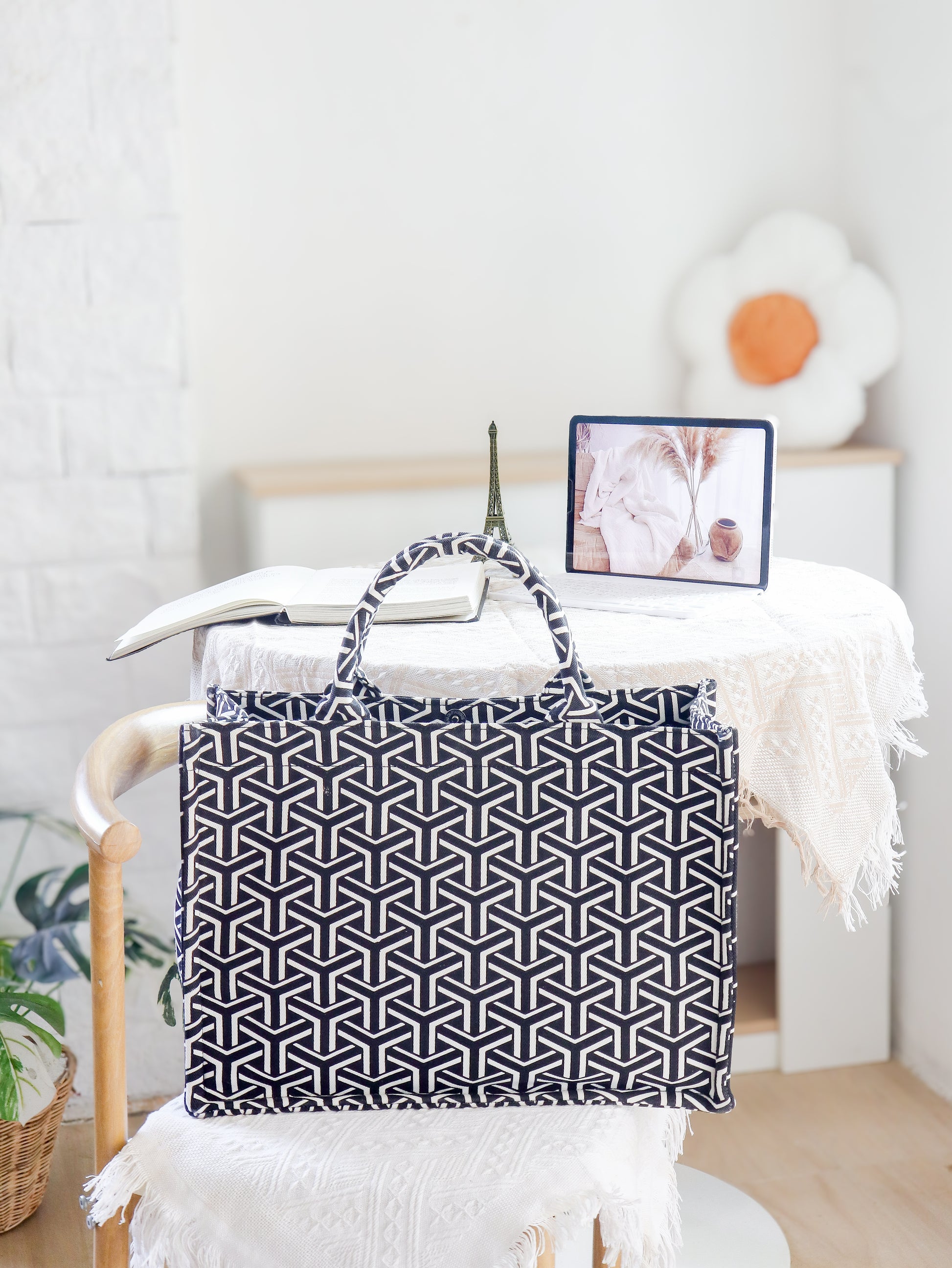 Black and white geometric patterned bag on a chair with a white wall and decor in the background