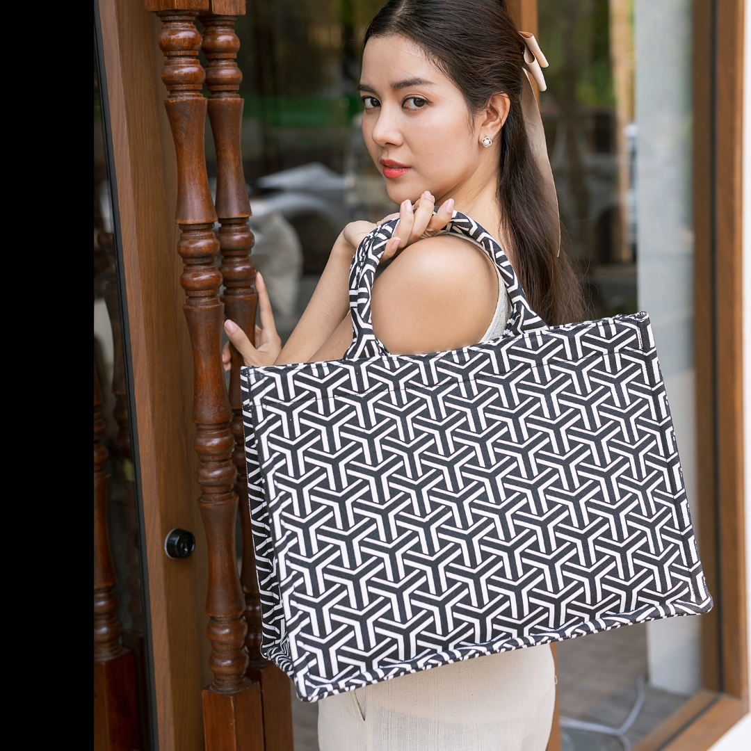Woman holding a black and white geometric patterned bag outdoors.