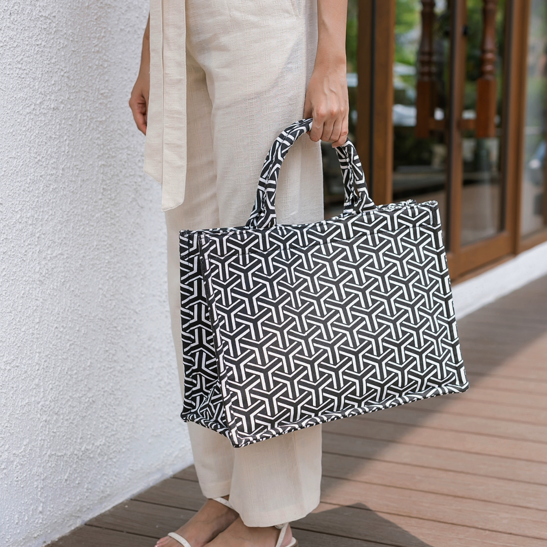 Person holding a black and white patterned bag outdoors.