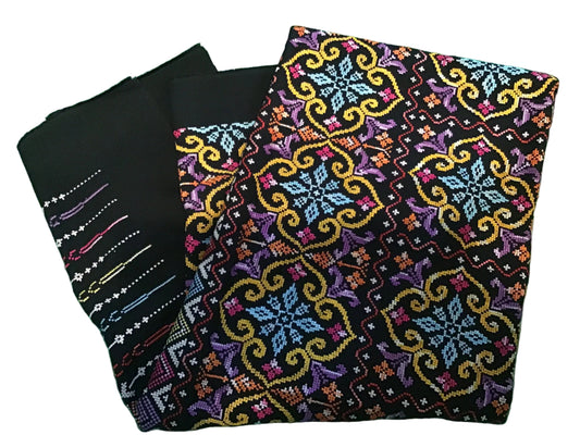 Black embroidered fabric has white, pink, blue, and yellow embroidered lines,  feature a complex multicolor geometric and floral pattern with yellow, blue, purple, and red details.