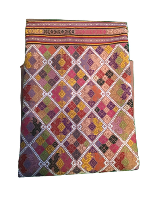 A folded multicolor patterned textile, likely a traditional woven bag or pouch, featuring a geometric diamond design in pink, orange, purple, yellow, and green .