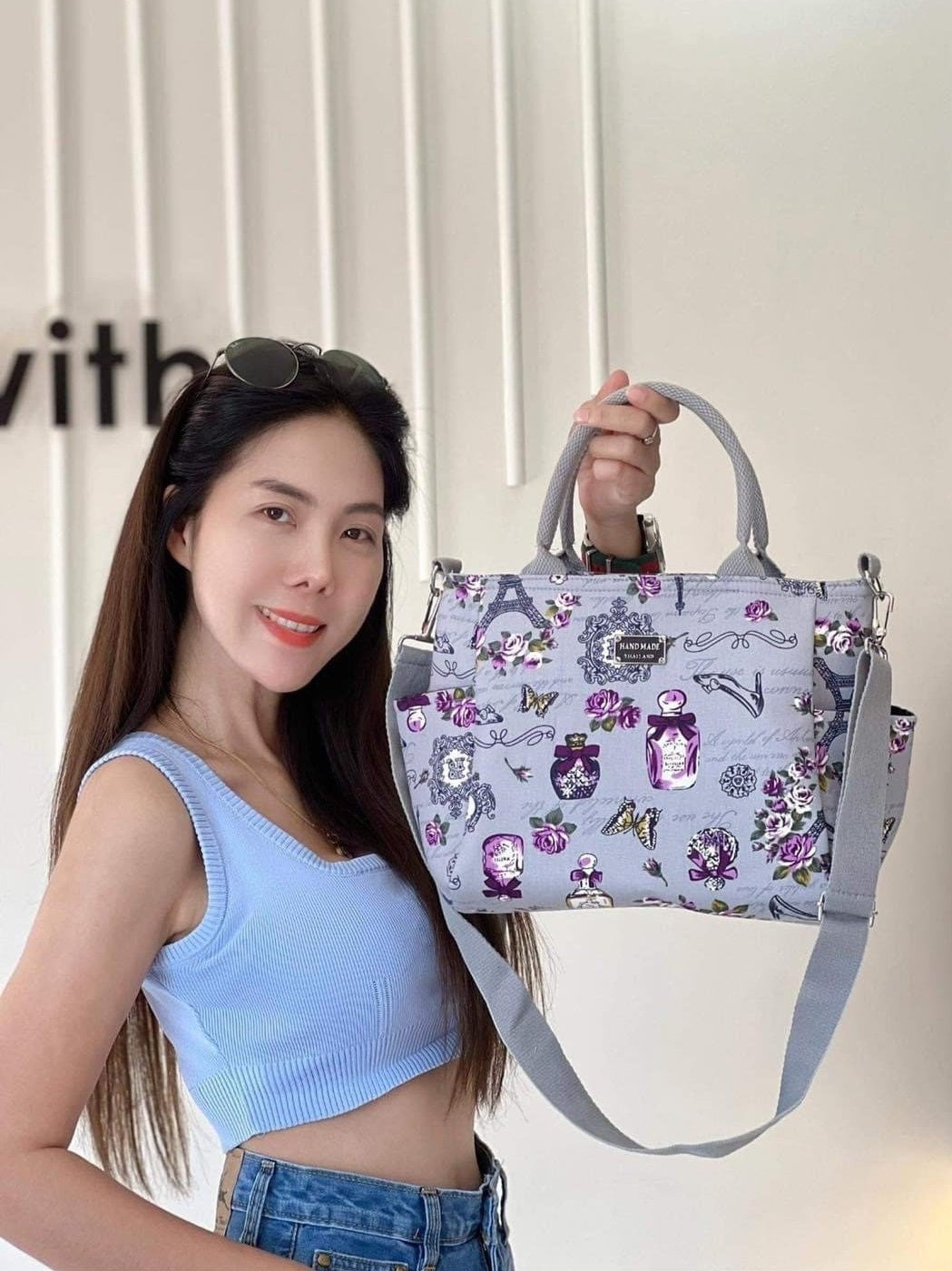 Thai Girl holding up a Handmade Thailand Handbag in Light Grey Fabric with Paris Eifel Tower and Perfume and Flower Pattern in Purple