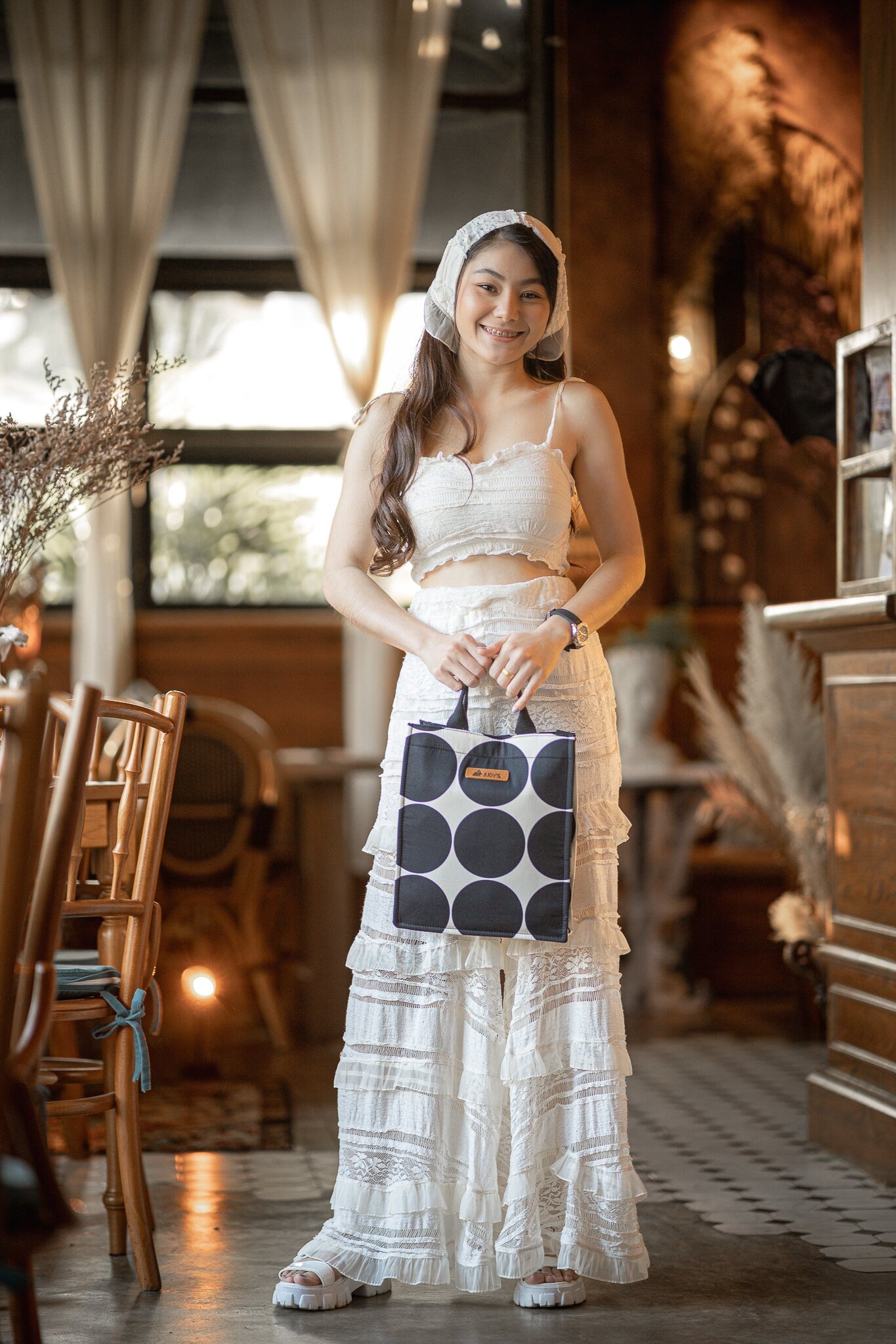 Thai girl smiling with iPad handbag in large black circle on white pattern.