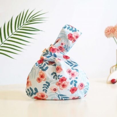 Japanese Knot Bag - Reversible and Compact Wrist Bag - Two Fabrics in One in a Pink and Blue Flowers on White background.