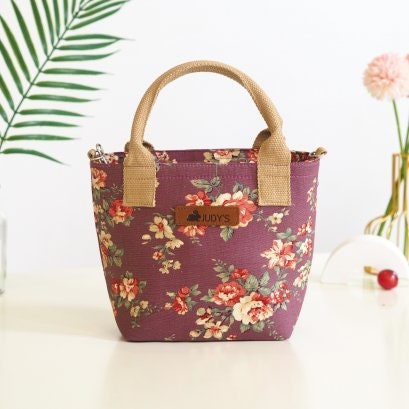 Small Top Handle handbag with shoulder strap in a floral print with White and Red Roses on a light Purple  background.