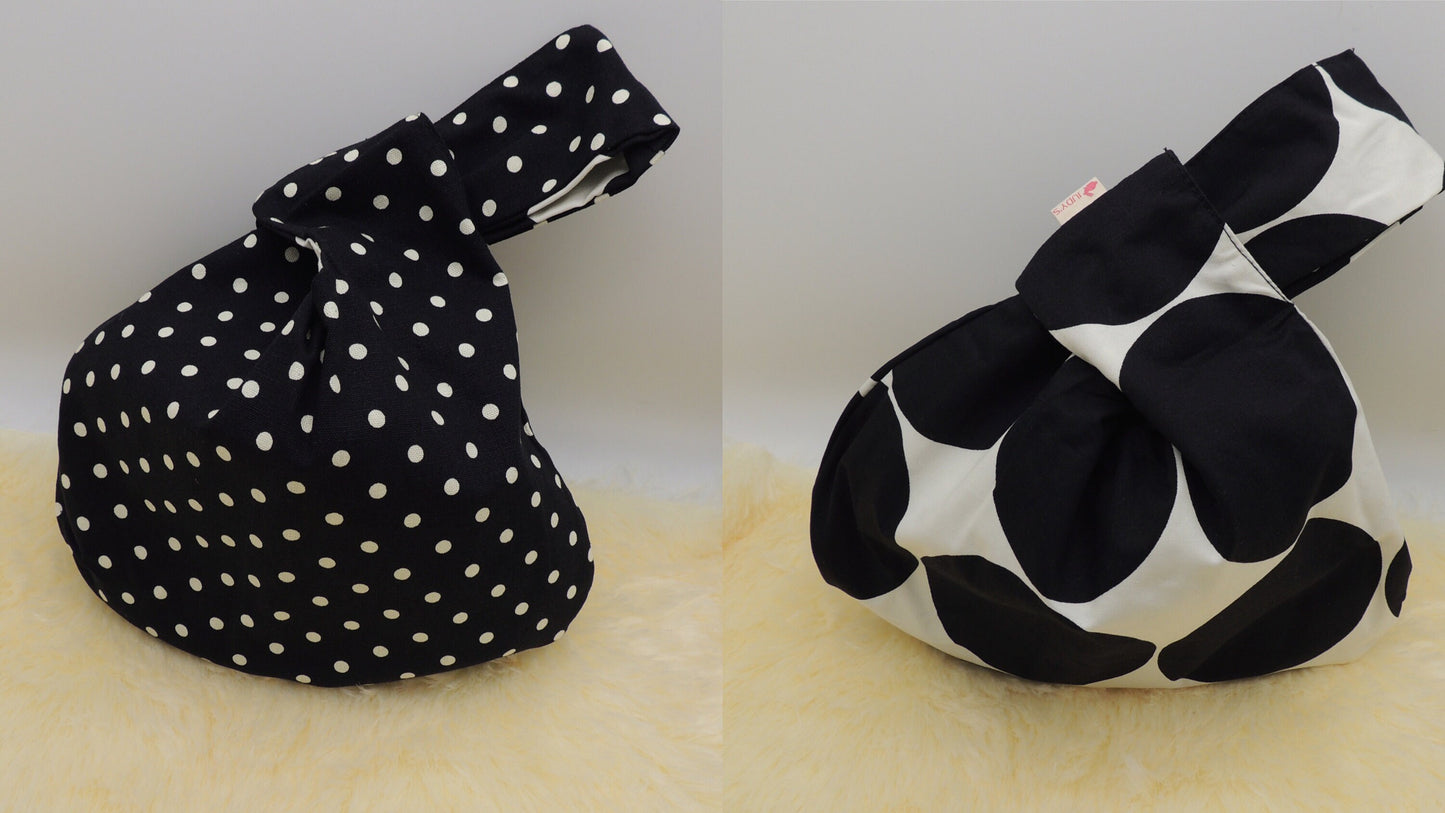 Japanese Knot Bag - Reversible and Compact Wrist Bag - Two Fabrics in One in a Large Black Circle and Small White Circle patterns.