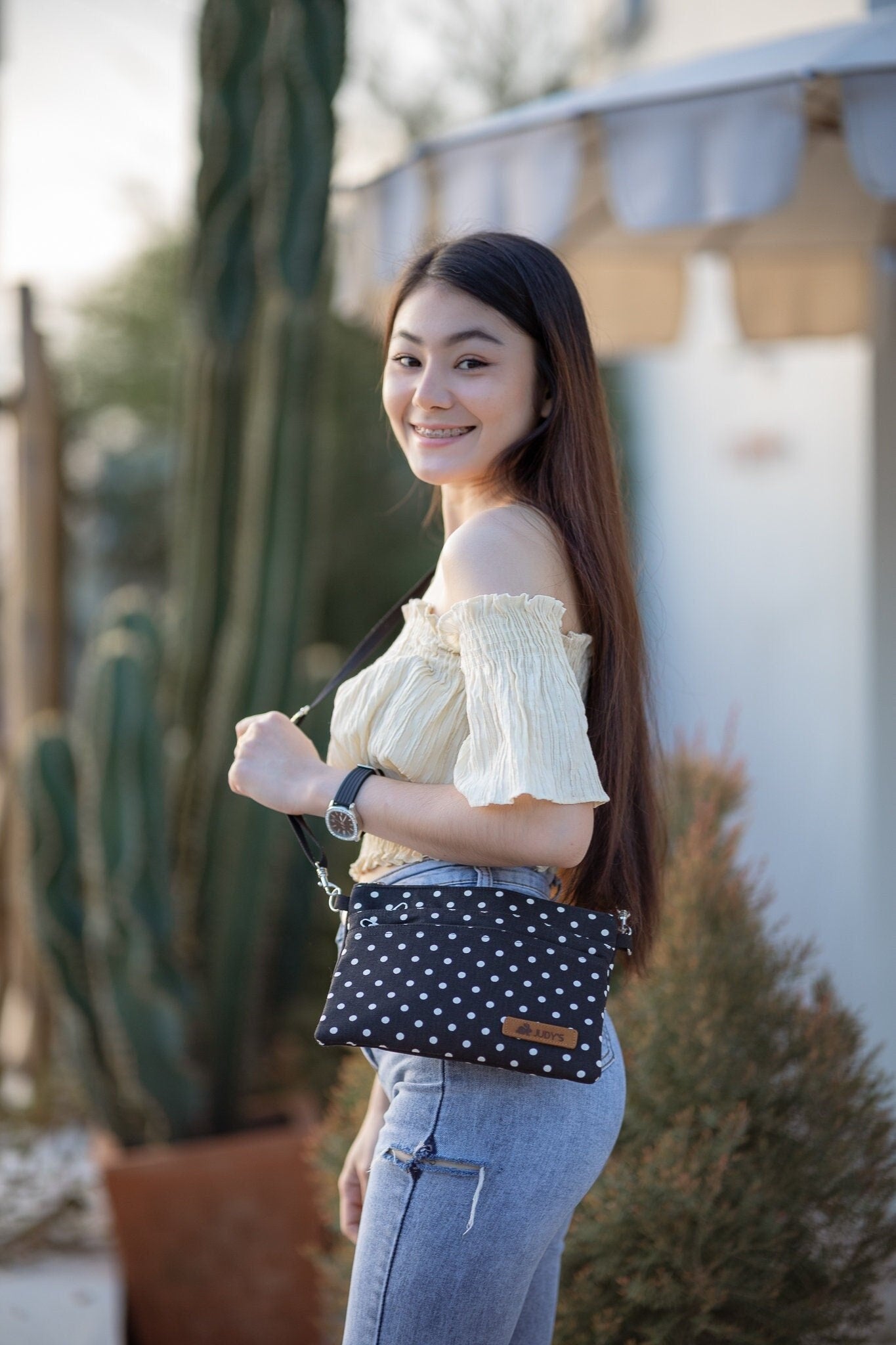 Thai girl with Cross Body bag in Black with Small White Circles pattern.